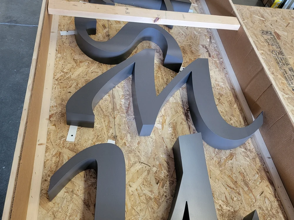 Fabricated reverse-pan metal letters prepared for installation