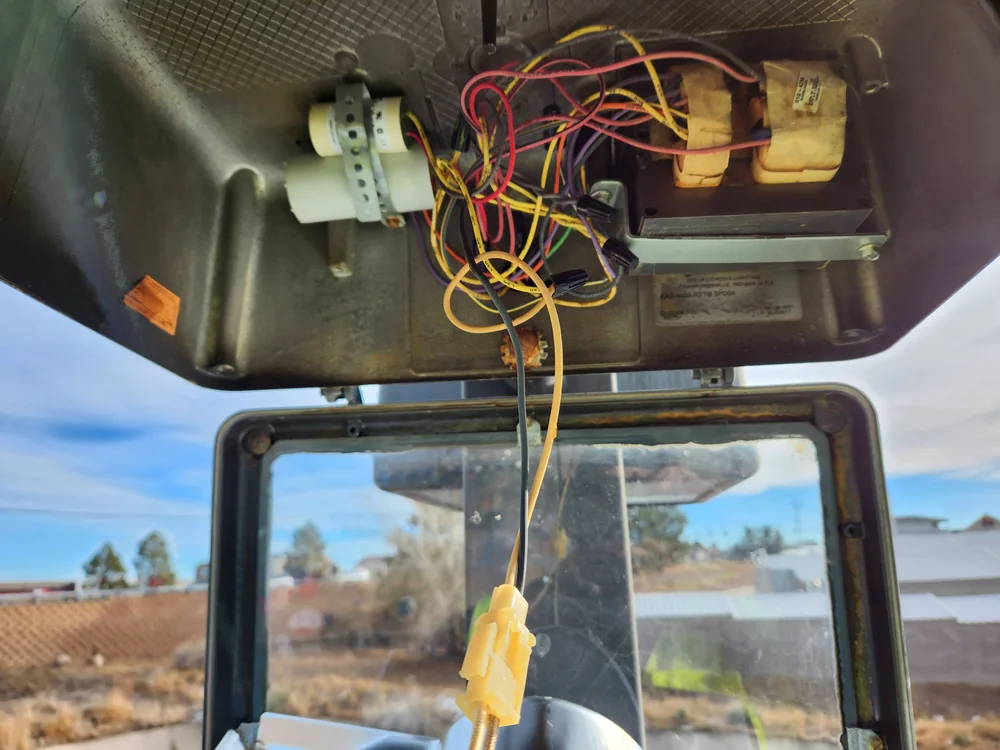 Open legacy parking lot light fixture showing wiring and older electrical components