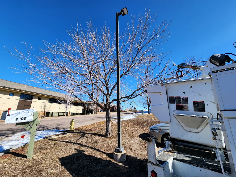 S2 bucket truck beside a commercial parking lot light pole during service