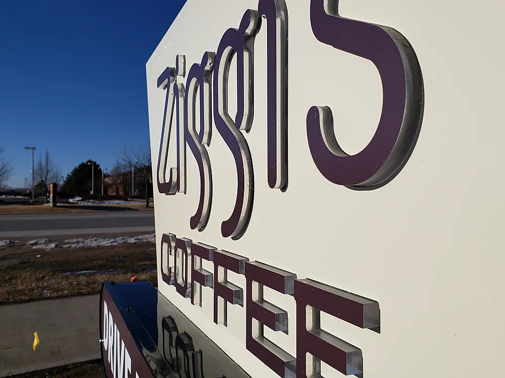 Close view of installed push-thru acrylic letters extending through a monument sign face